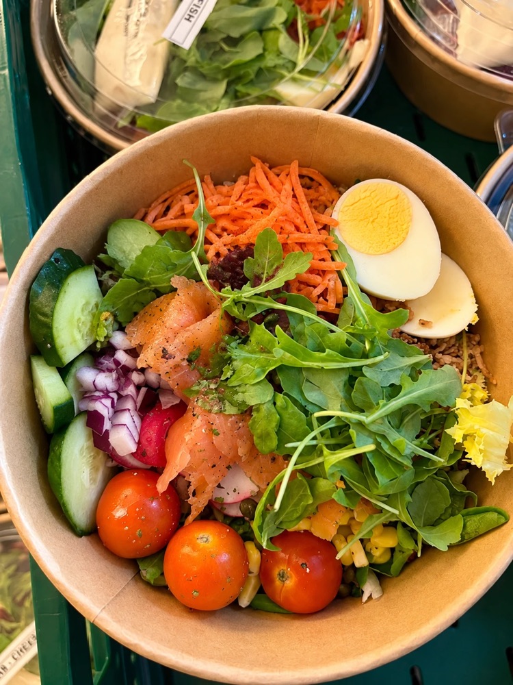 Salade met gerookte zalm, ei, rucola en kerstomaatjes in een kartonnen kom